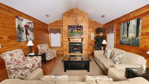 A cozy log cabin interior with a fireplace, two sofas, a coffee table, and wooden walls. - Wildwood Falls 4 - Two Bedroom Chalet (Pigeon Forge)