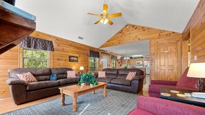A cozy living room with wooden walls, a ceiling fan, and two sofas. - Poplar Point Condo Unit 12D - Two Bedroom Condo (Pigeon Forge)