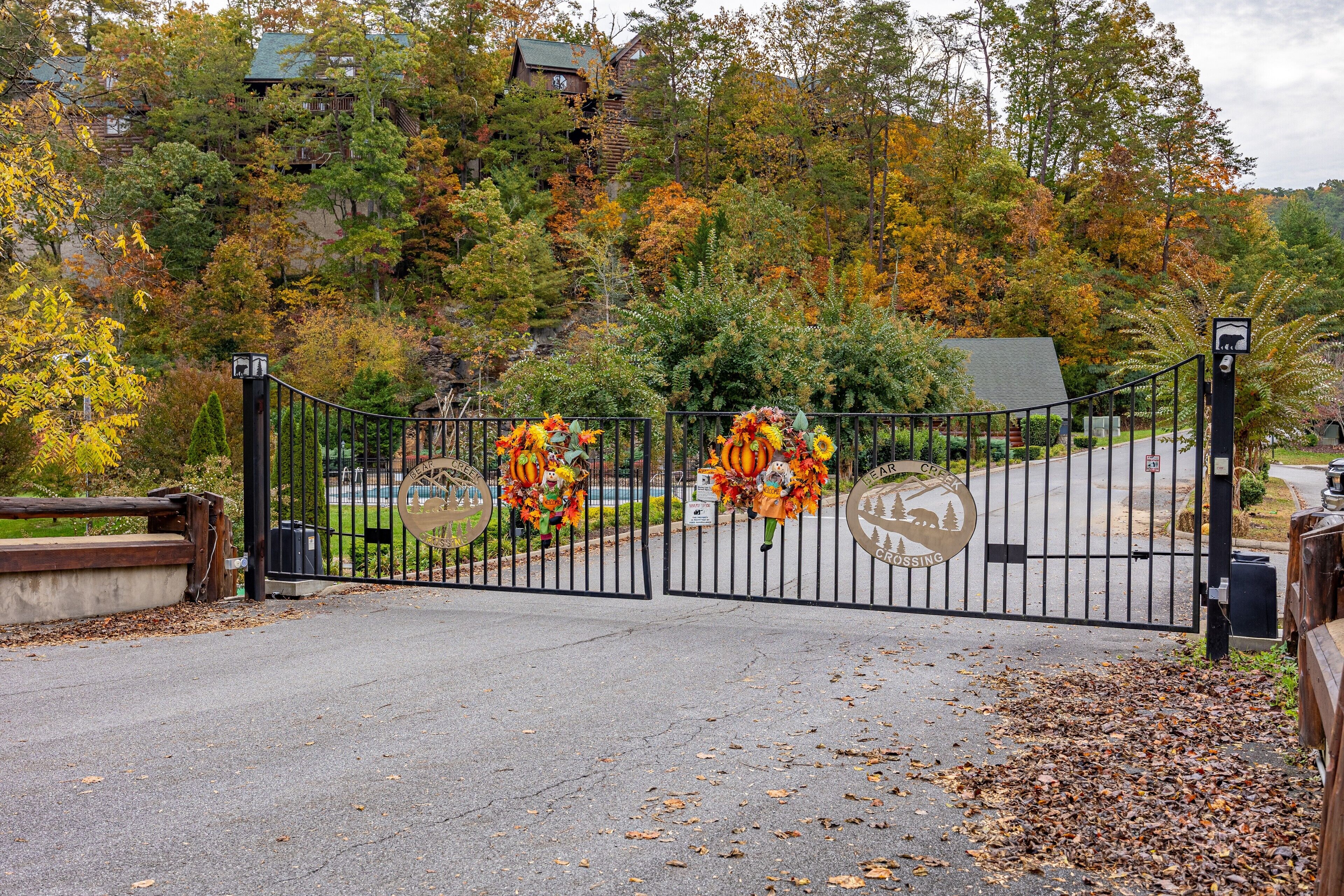 A gated entrance with autumn foliage and decorative wreaths.