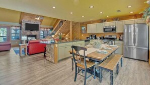 A spacious kitchen with a wooden island, stainless steel appliances, and a cozy seating area with a fireplace. - Splash Mountain Lodge (Gatlinburg)