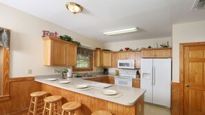Una cocina con armarios de madera, un refrigerador blanco, un microondas y una isla grande con taburetes.