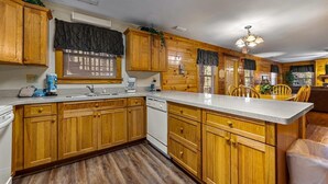 Una cucina con mobili in legno, lavastoviglie e una grande isola con sedie.