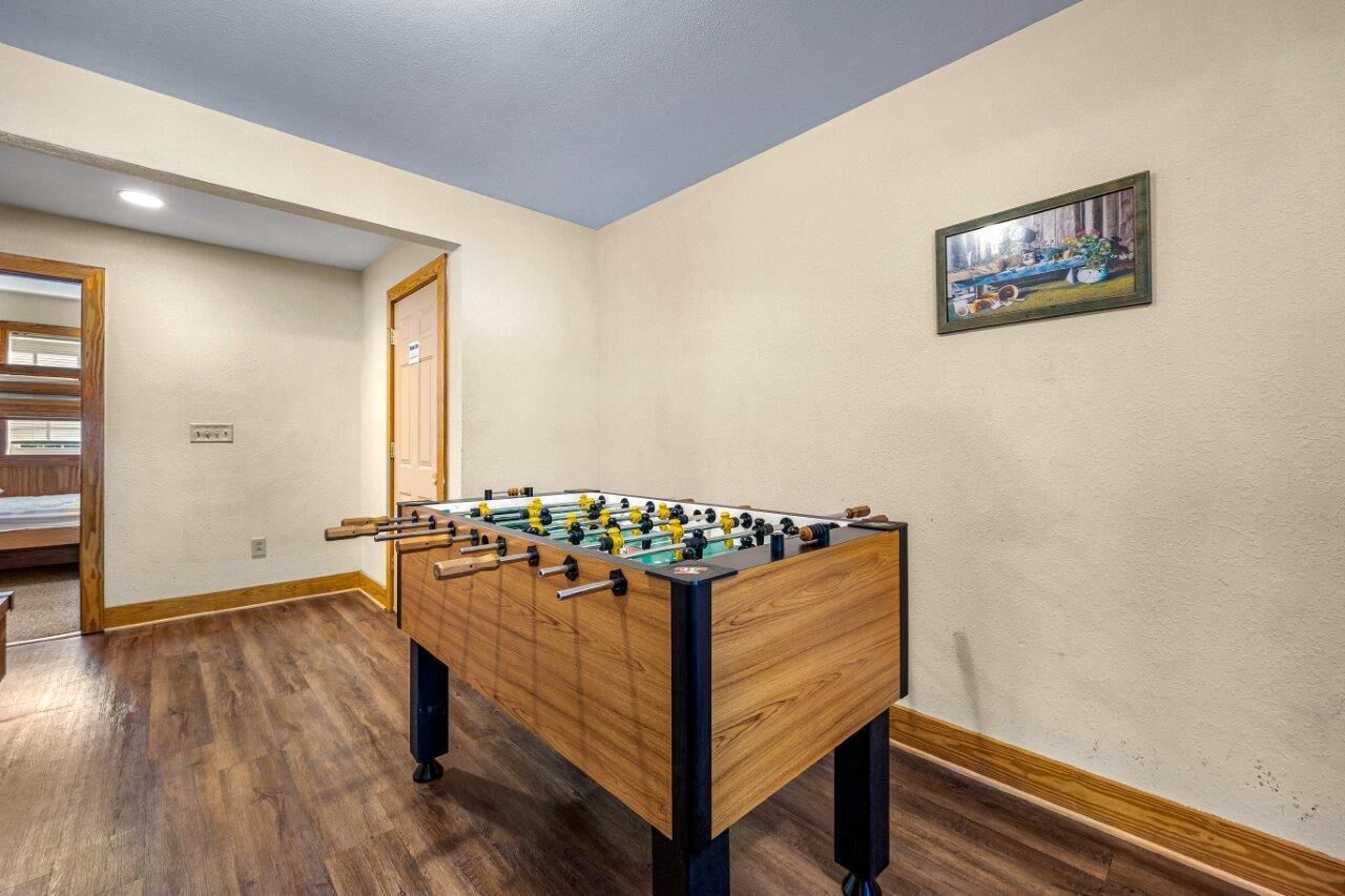 Une pièce avec un baby-foot en bois, une porte et un tableau accroché au mur.