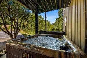 A hot tub with a wooden exterior and a view of trees and a building in the background.