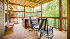 A wooden deck with a hot tub, two chairs, and a table. - Marco Polo - Four Bedroom Chalet (Gatlinburg)