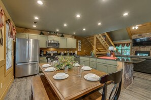 Une cuisine moderne avec coin repas, dotée d’appareils électroménagers en acier inoxydable, de meubles en bois et d’une cheminée en pierre.