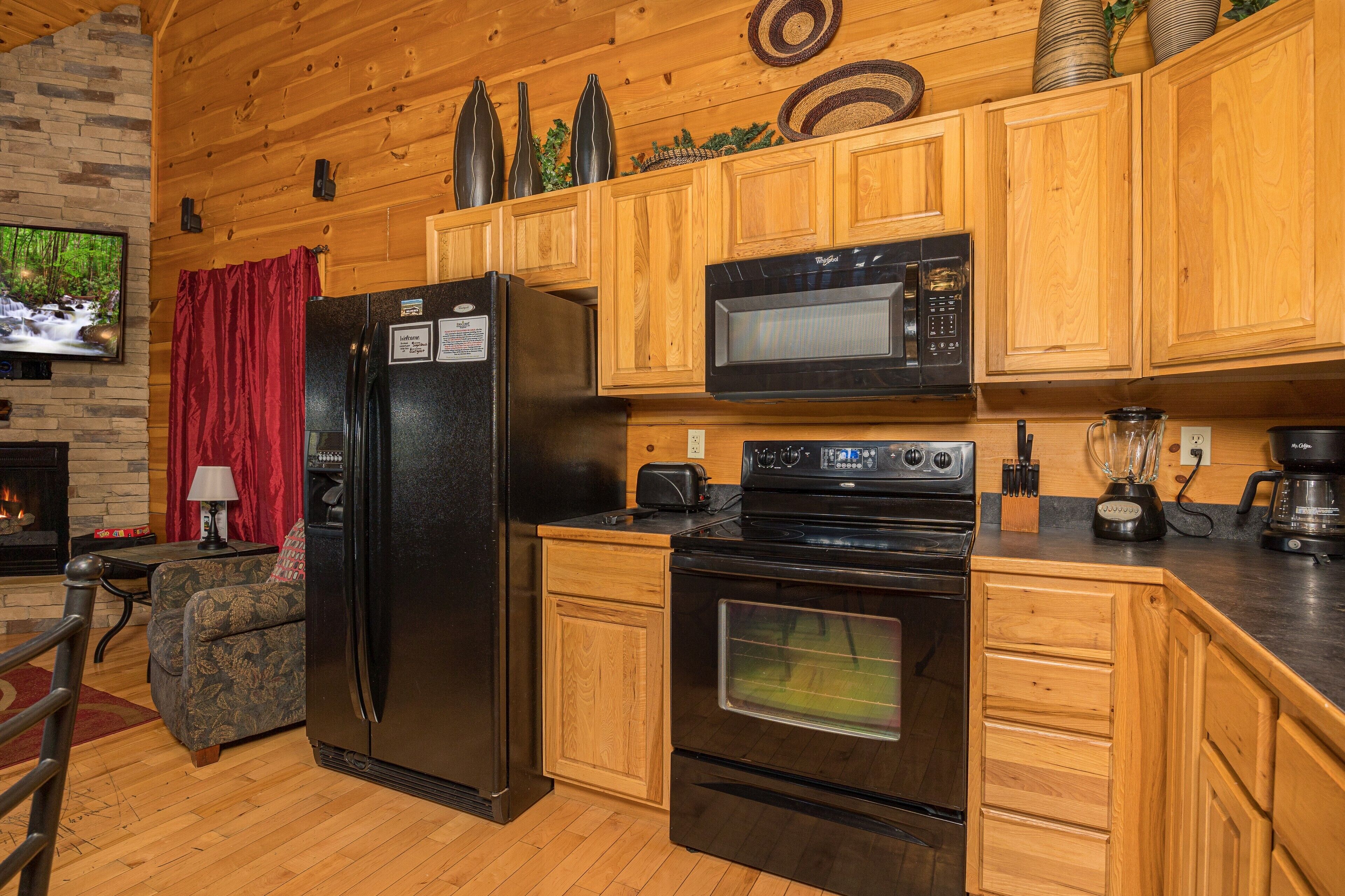 A kitchen with wooden cabinets, a black refrigerator, a microwave, and an oven.