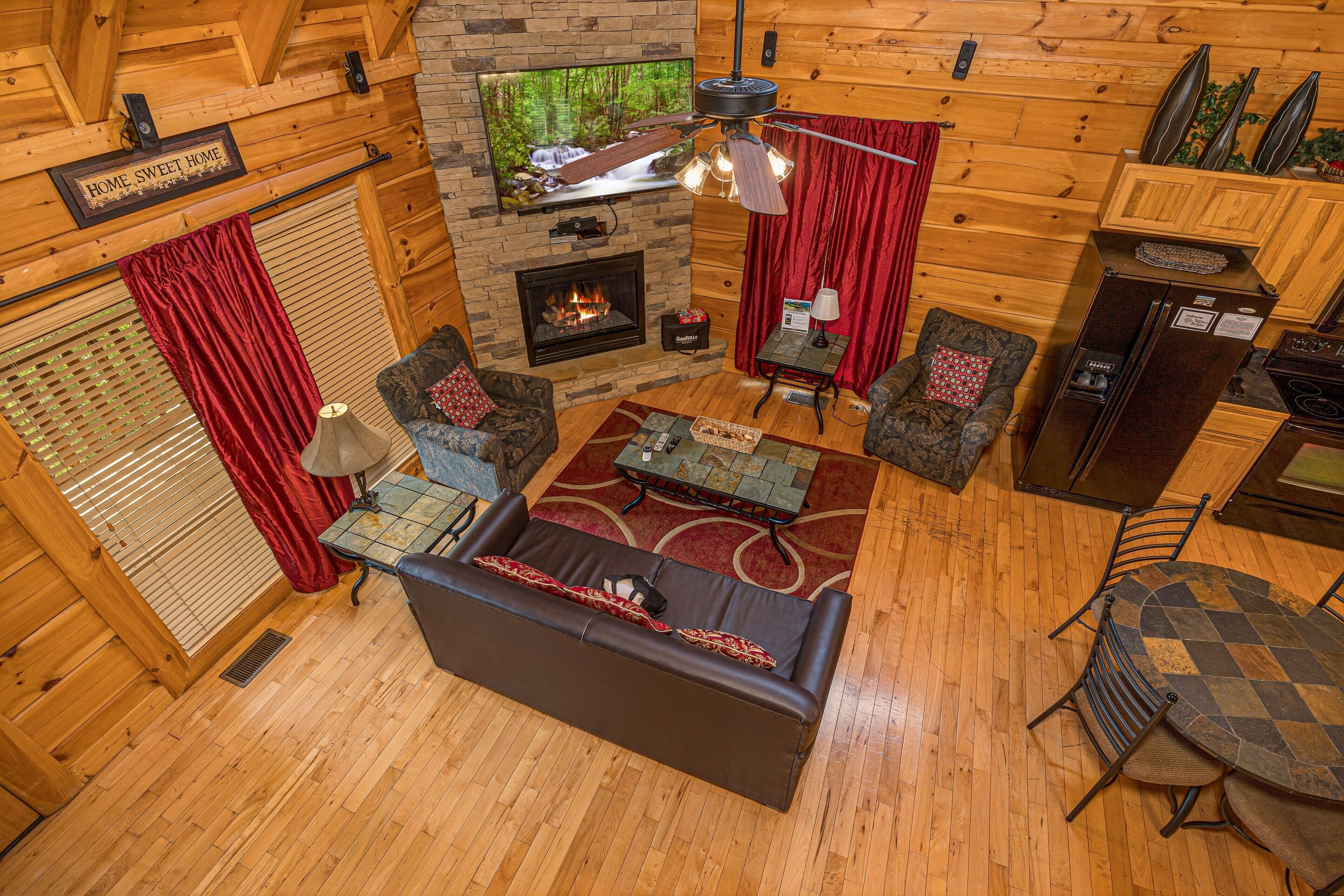 A cozy cabin interior with a fireplace, wooden walls, a sofa, a coffee table, and a dining area.