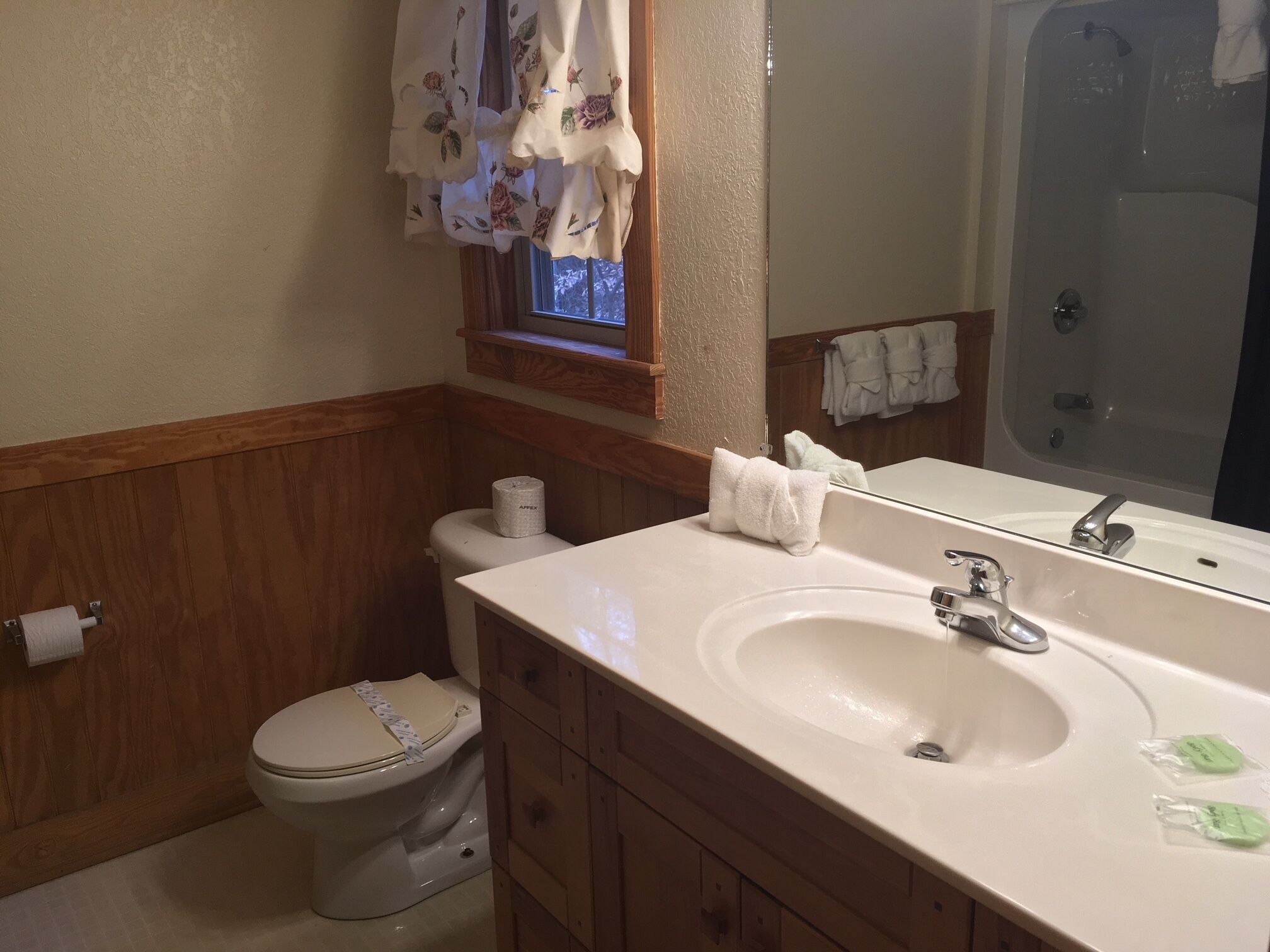 Une salle de bain avec un meuble-lavabo en bois, un évier, des toilettes et un espace douche.