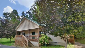 A single-story house with a porch, a small staircase, and a wooden fence.