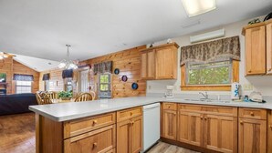 A kitchen with wooden cabinets, a white countertop, and a dishwasher. - Poplar Point Condo Unit 12B - Two Bedroom Condo (Pigeon Forge)