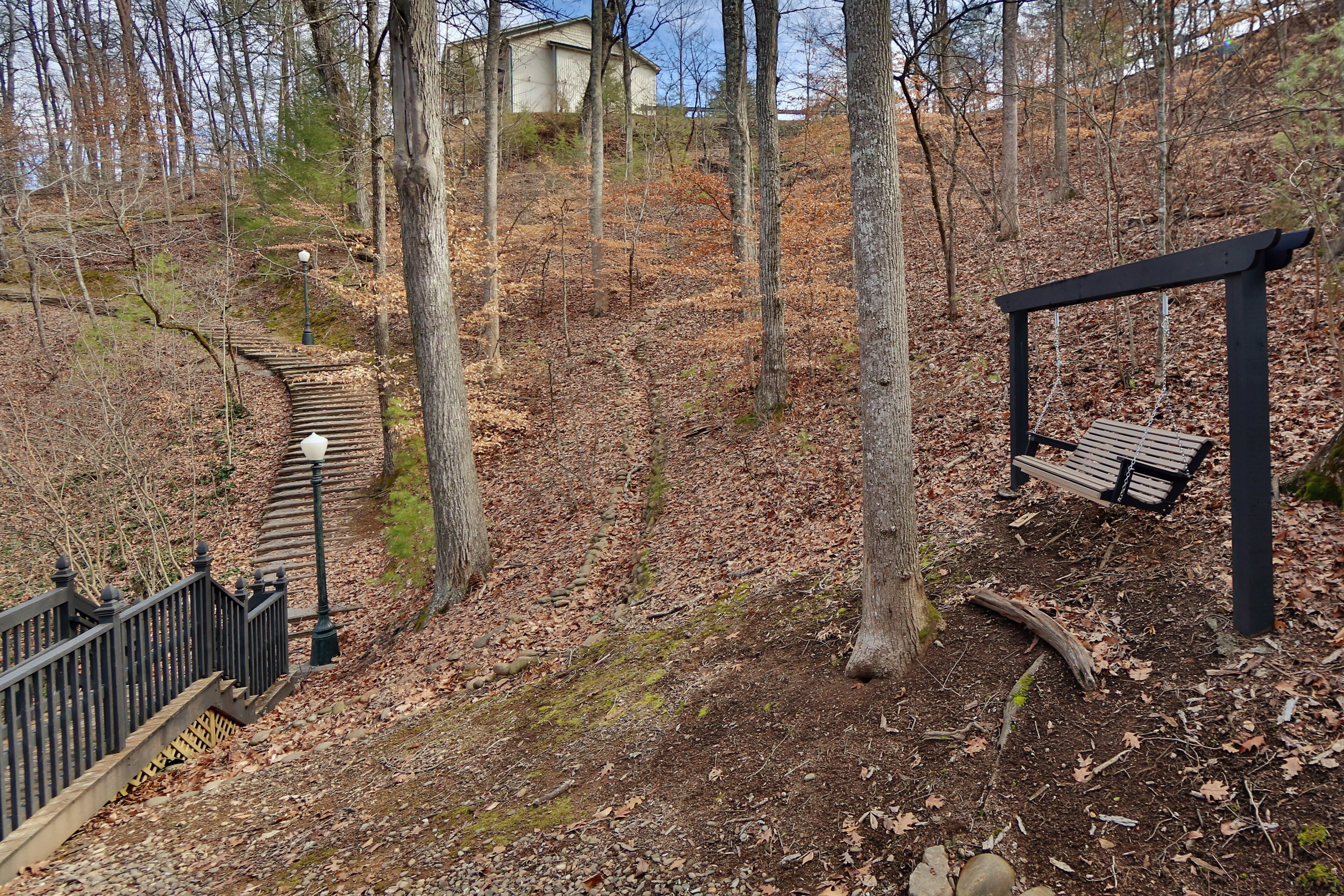 Ein Park mit einer hölzernen Bank, einer Steintreppe und einem Metallgeländer.
