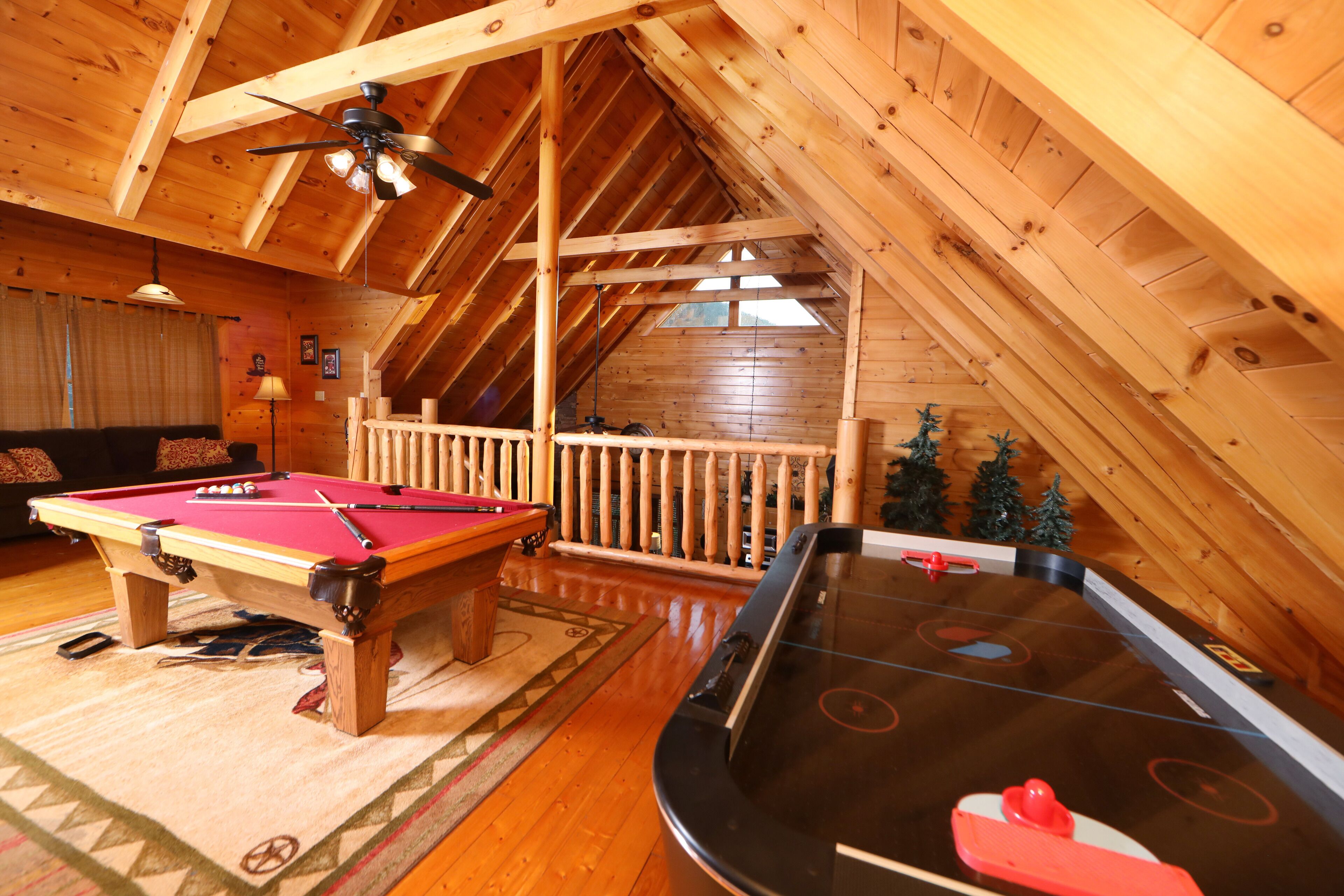 An indoor recreational area with a pool table, shuffleboard table, and a wooden deck.
