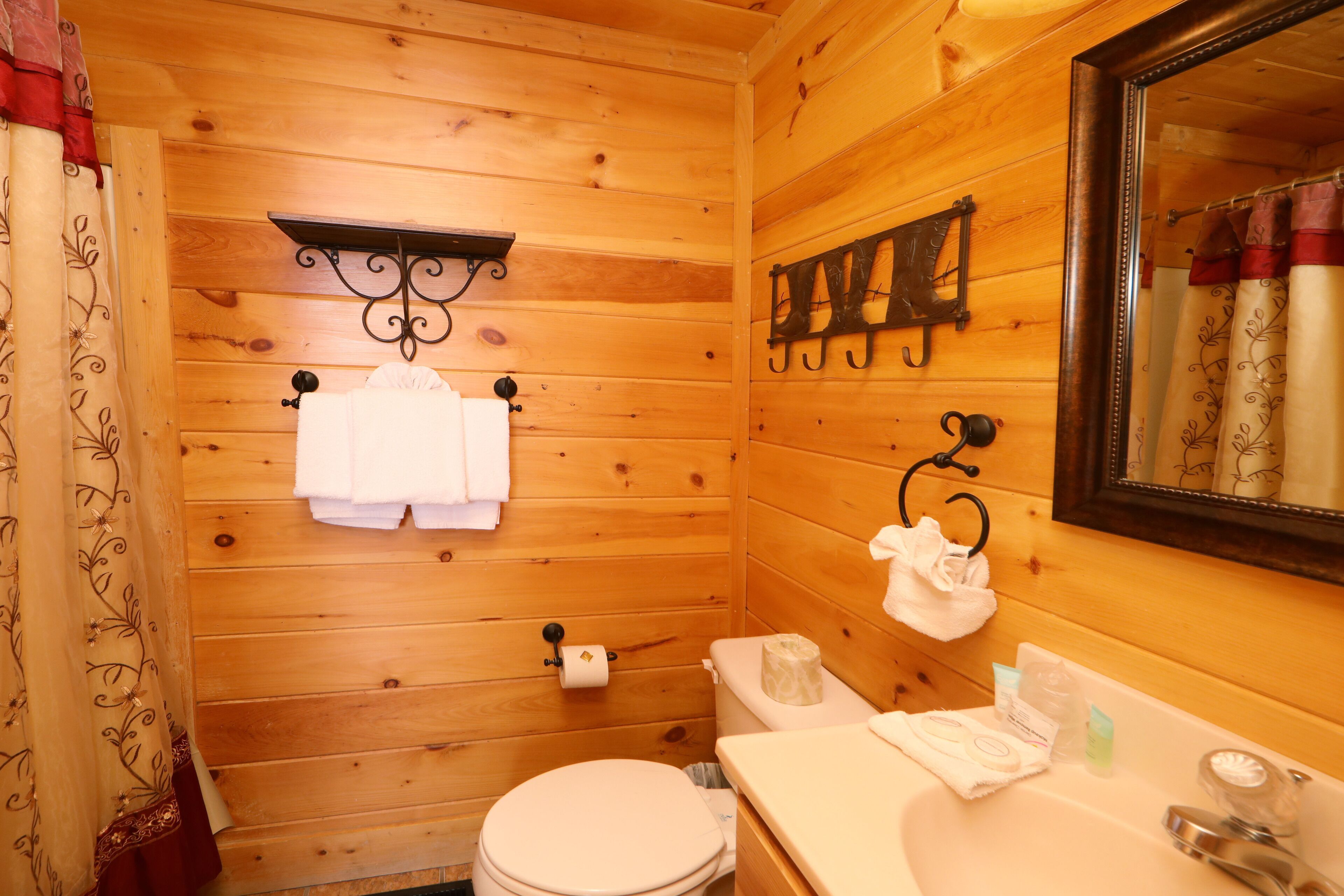 Bagno di una baita in legno con il water, un lavabo e uno specchio.