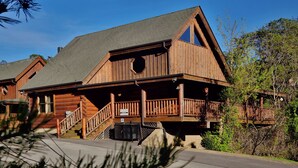 A wooden cabin with a balcony, a staircase, and a clear sky.