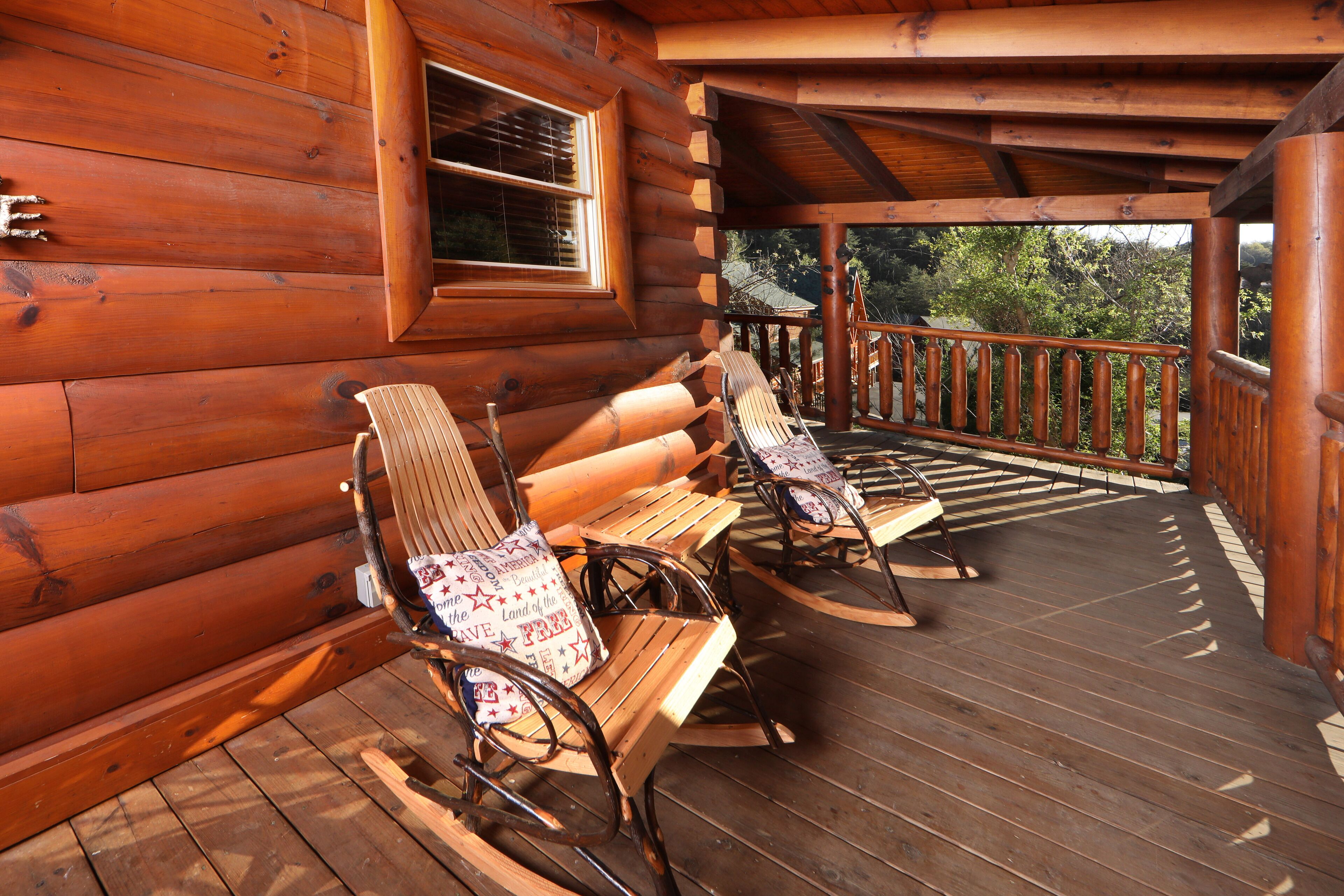 Eine Holzhütte mit einer Veranda, auf der Schaukelstühle und ein Holztisch stehen.