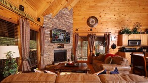 A cozy living room with a leather sofa, a fireplace, wooden walls, and a television.
