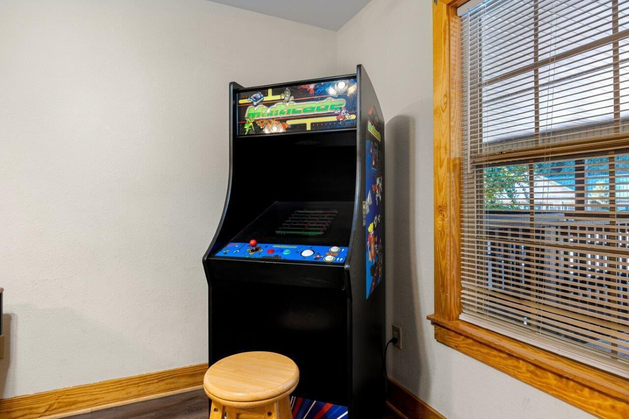 A small arcade machine with a wooden stool in front.