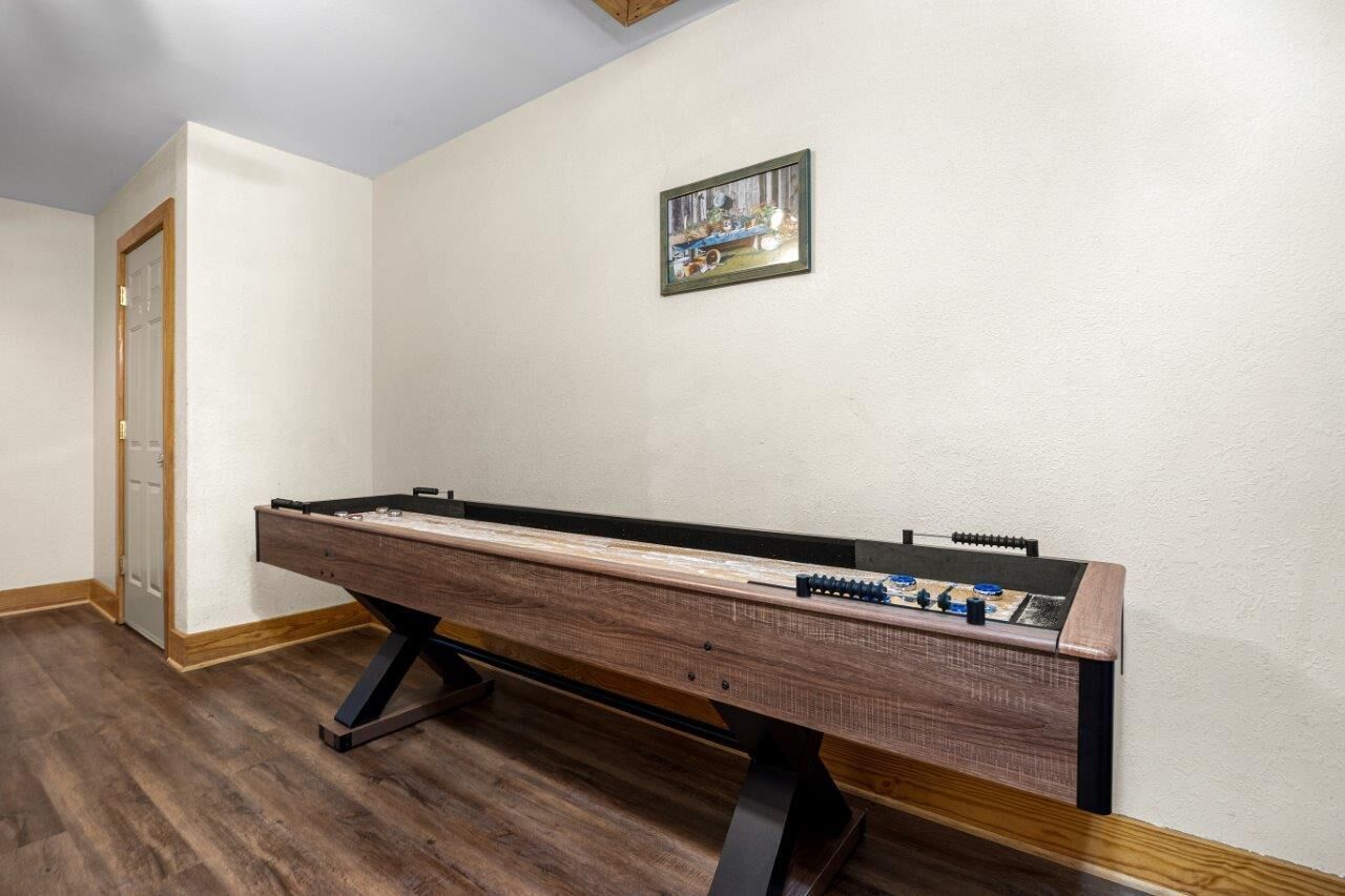 A pool table in a room with wooden flooring and white walls.