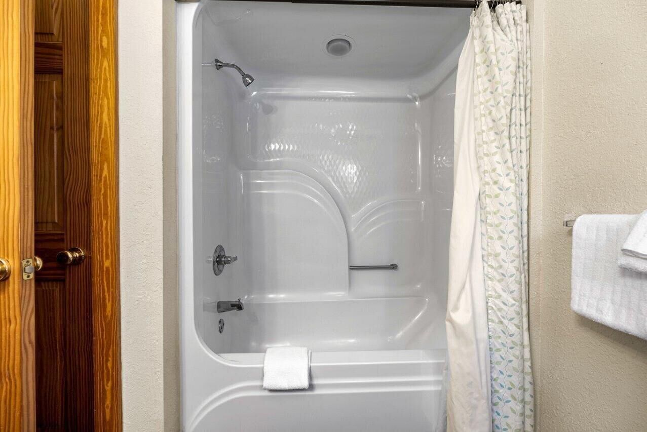 A bathroom with a bathtub, a shower curtain, and a towel rack.