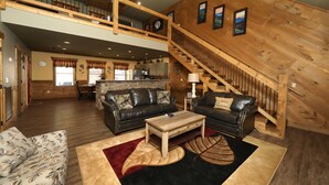 A spacious living area with a high ceiling, wooden staircase, and a dining area in the background. - Splash Time Cinema - Six Bedroom Chalet (Gatlinburg)