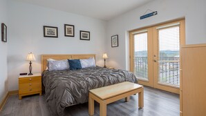 A bedroom with a bed, bedside tables, a bench, and a wardrobe. - Mountain View Condo 1205 - Two Bedroom Condo (Pigeon Forge)