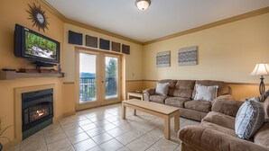 A living room with a fireplace, a television, a sofa, and a coffee table. - Mountain View Condo 1205 - Two Bedroom Condo (Pigeon Forge)