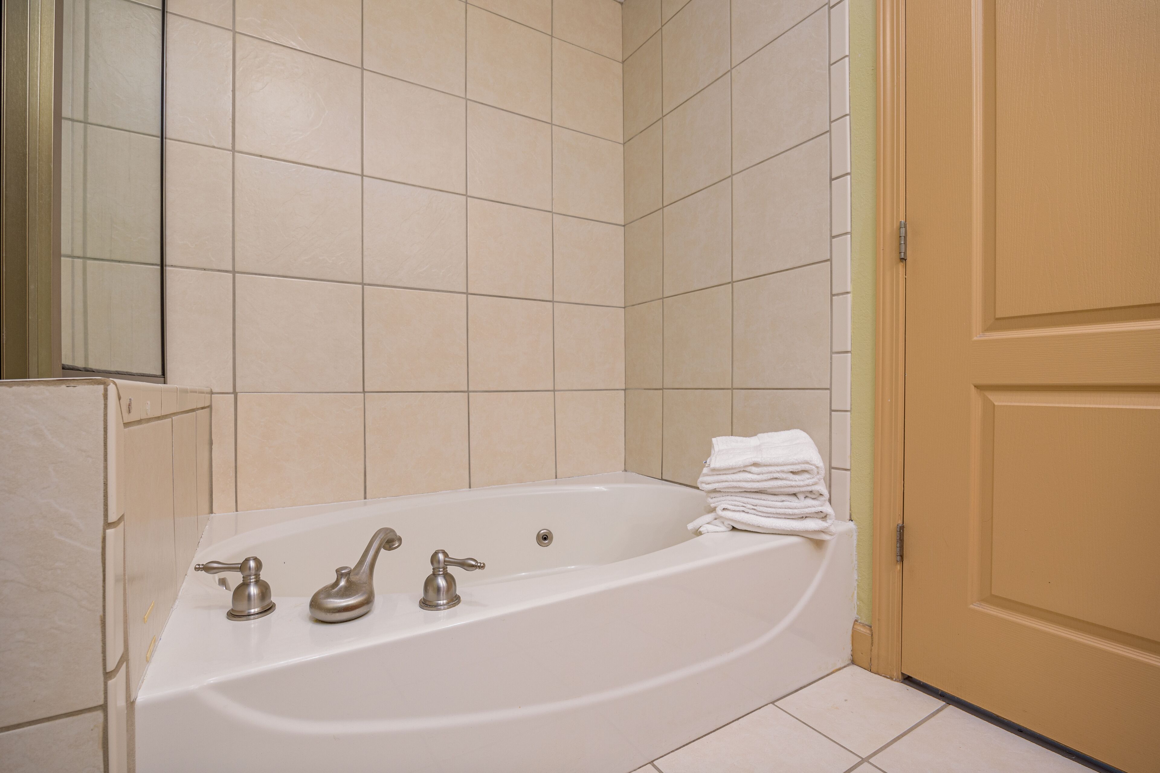 Un baño con una bañera, dos llaves y una pila de toallas blancas.