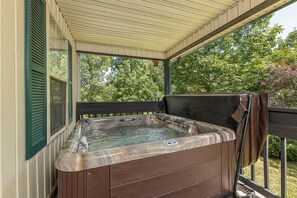 A hot tub on a covered porch with a wooden deck and a view of trees. - Magnolia Place 5 - Eight Bedroom Chalet (Pigeon Forge)