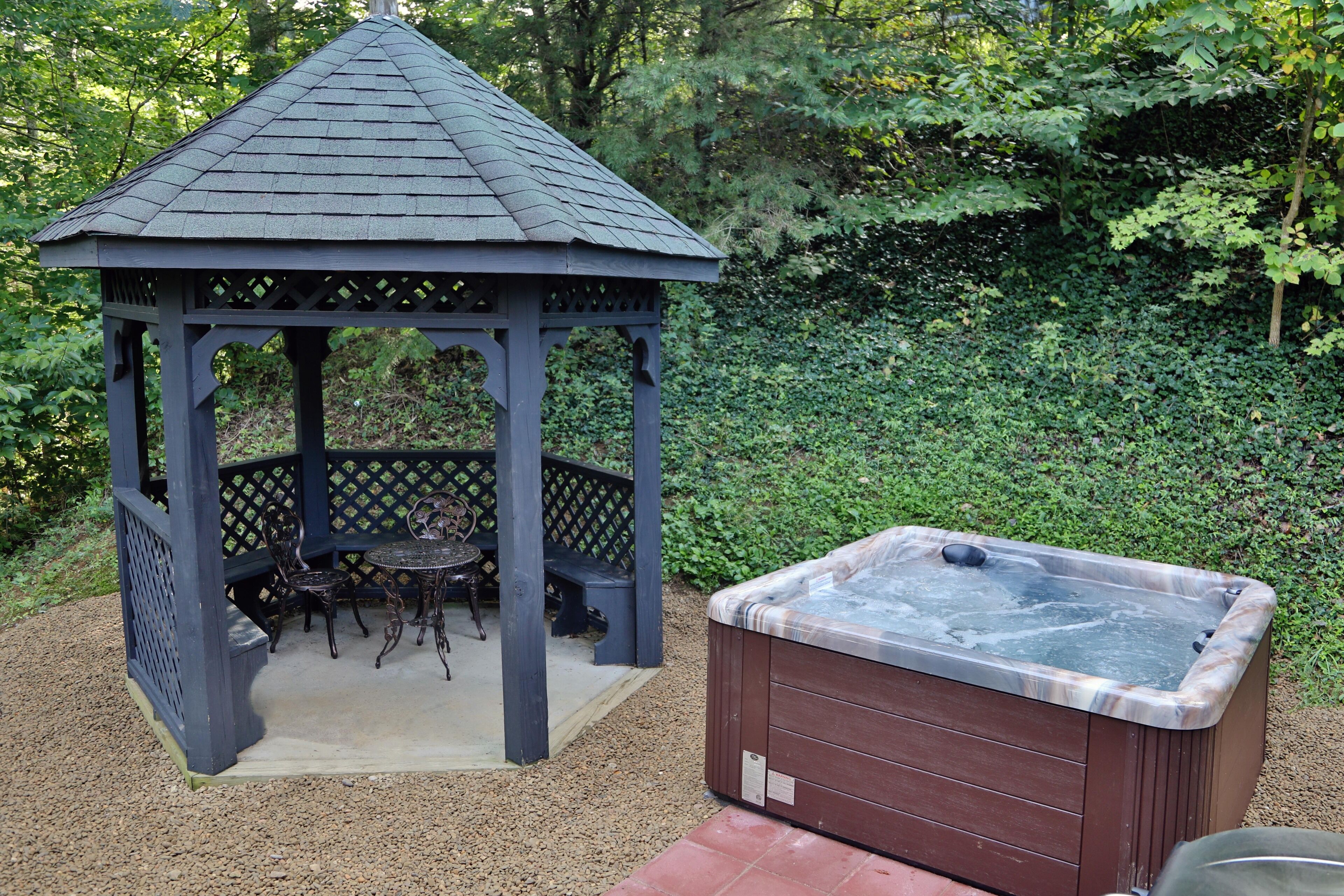 A gazebo with a table and chairs, and a hot tub.