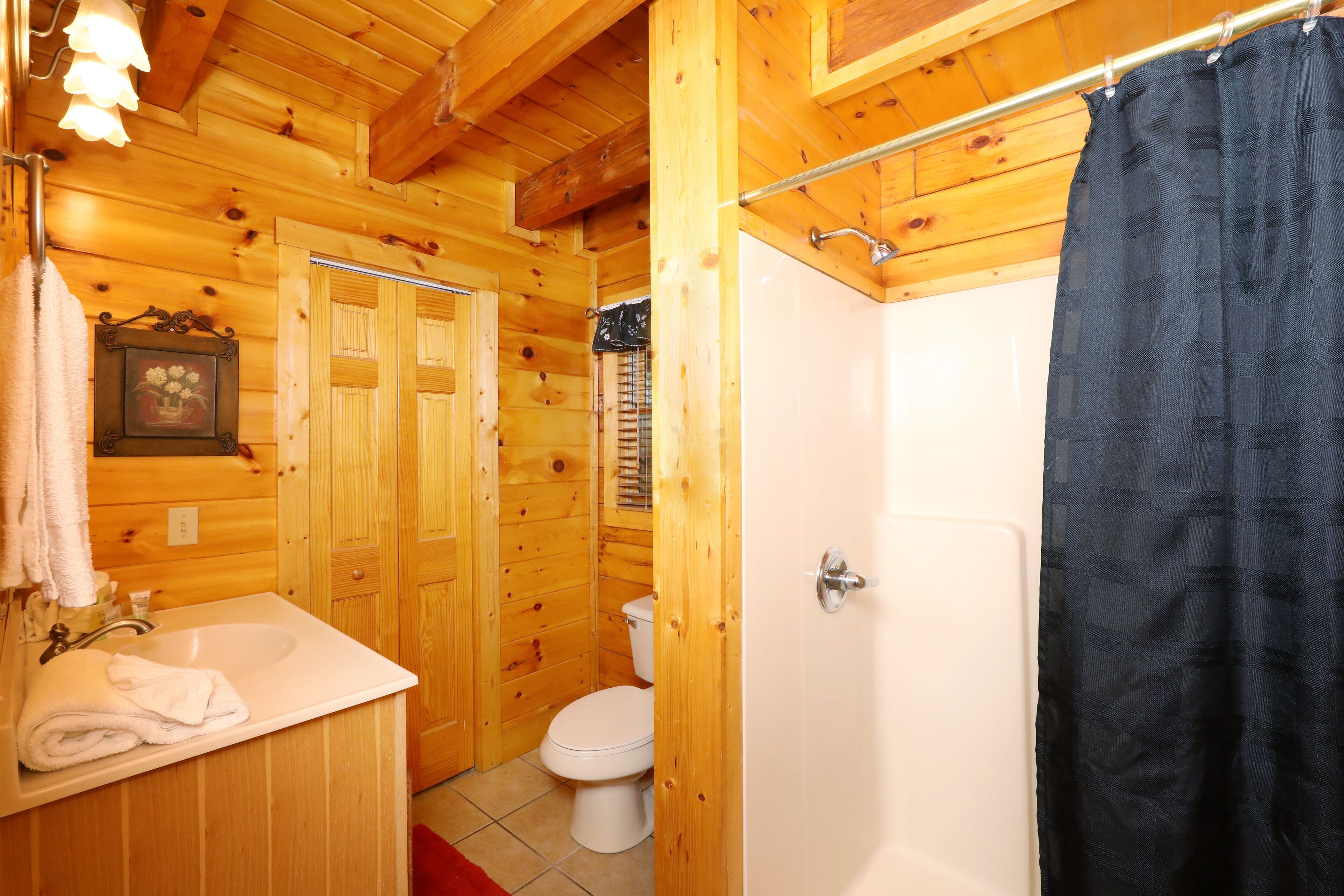 Ein Badezimmer einer Holzhütte mit Waschbecken, Toilette und Duschvorhang.