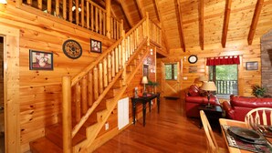 Un intérieur en bois avec un escalier, un canapé en cuir rouge et un coin repas.