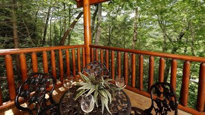 Une terrasse en bois avec une rambarde, entourée d’arbres.