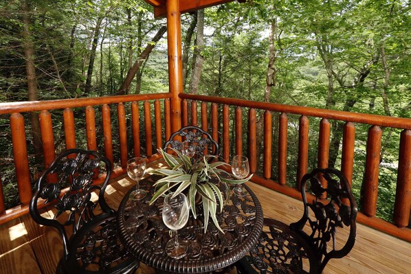 A wooden deck with a railing, surrounded by trees.
