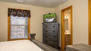 A bedroom with a bed, a dresser, a television, and a window with blinds. - Briarstone Lodge Condo 13F - Three Bedroom Condo (Pigeon Forge)