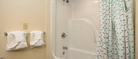 A bathroom with a bathtub, a shower, and two towels hanging on a rack.