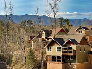 A cluster of cabins with multiple stories, wooden balconies, and a mountainous backdrop. - Hilltop Haven - Four Bedroom Chalet (Gatlinburg)