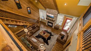 A spacious living area with a fireplace, wooden flooring, and a cozy seating arrangement. - Hilltop Haven - Four Bedroom Chalet (Gatlinburg)