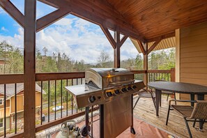 A covered outdoor area with a stainless steel grill, a table, and chairs. - Hilltop Haven - Four Bedroom Chalet (Gatlinburg)