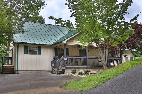 A two-story building with a green roof, a front porch, and a staircase leading to the entrance. - Holly Grove 1 - Three Bedroom Chalet (Pigeon Forge)