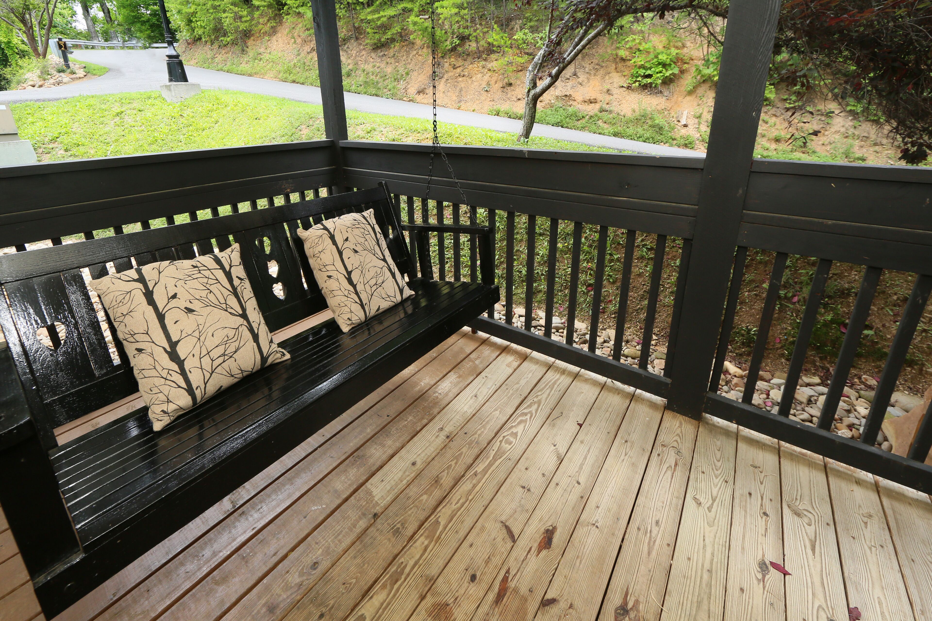 A wooden deck with a bench and a view of a landscaped area.