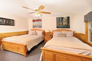 A bedroom with two wooden beds, a ceiling fan, and artwork on the walls. - Holly Grove 1 - Three Bedroom Chalet (Pigeon Forge)