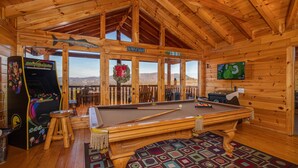 A wooden interior with a pool table, a pinball machine, and a TV screen. - Picture Perfect- Seven Bedroom Cabin (Sevierville)