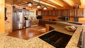 A modern kitchen with granite countertops, stainless steel appliances, and wooden cabinetry. - Picture Perfect- Seven Bedroom Cabin (Sevierville)