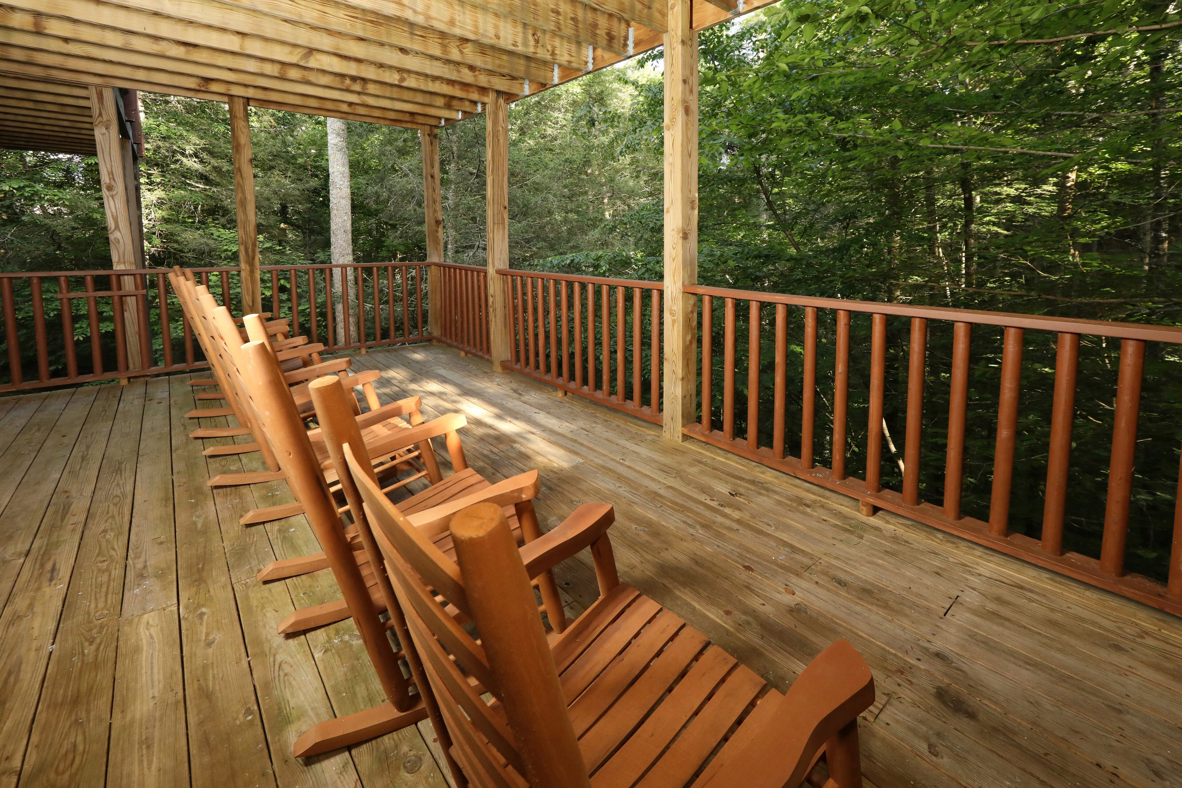 A wooden deck with benches and a railing overlooking a forested area.