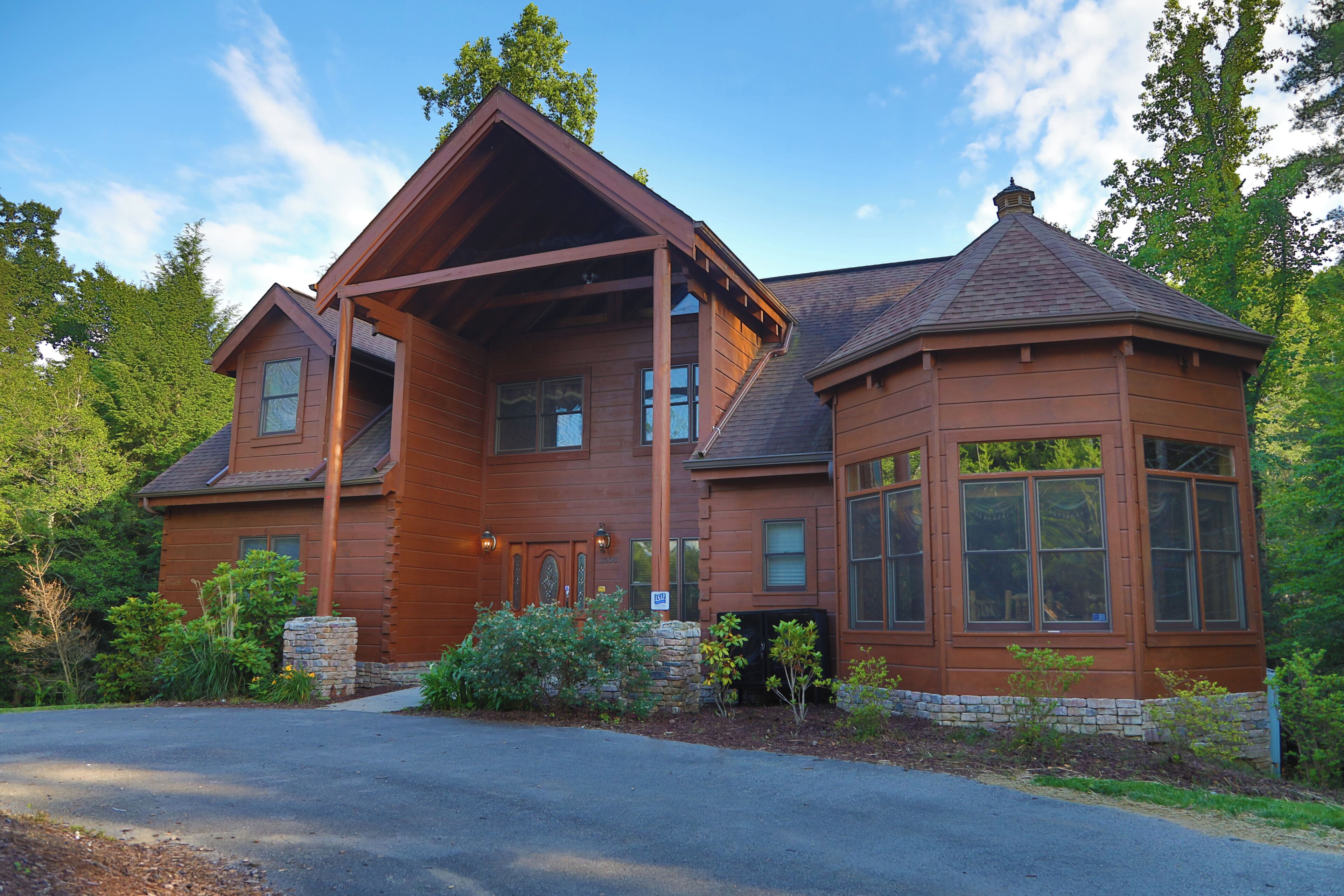 A large, two-story log cabin with a prominent porch and a turreted section.