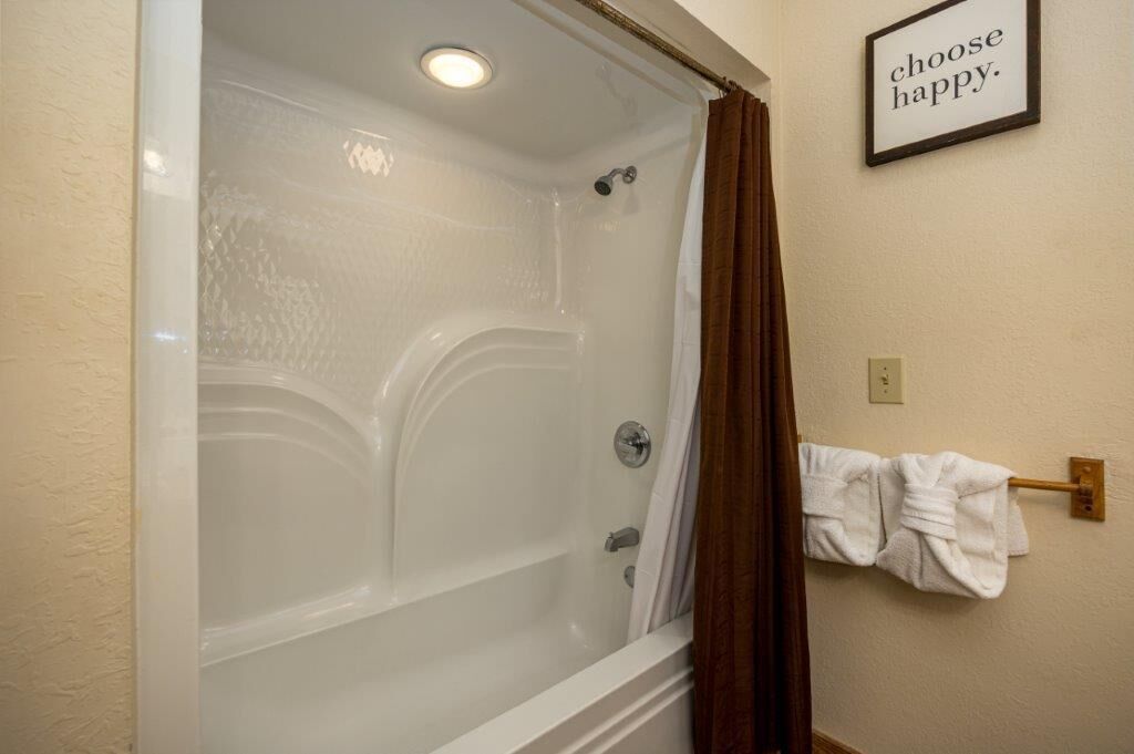 A bathroom with a glass-enclosed shower, a towel rack with towels, and a motivational quote on the wall.