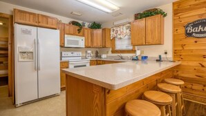 Una cocina con armarios de madera, un refrigerador blanco, un microondas, una cafetera e isla de madera con taburetes.