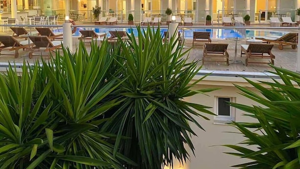 A multi-story hotel with a swimming pool, outdoor seating, and balconies.