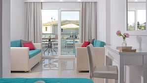A modern hotel room with a balcony, a dining area, and a desk with a vase of flowers.